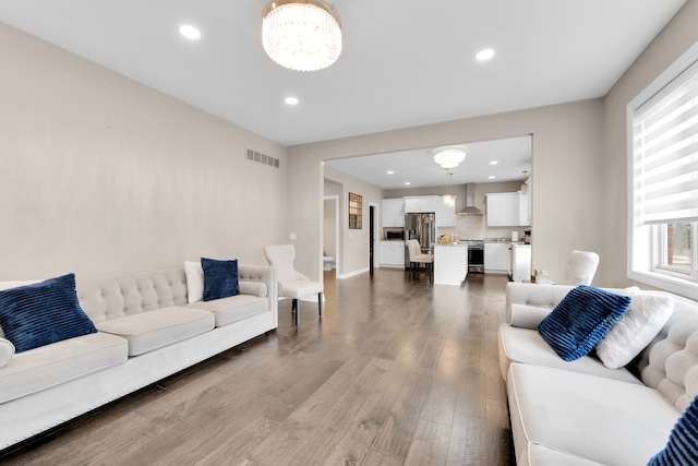 living area featuring a notable chandelier, visible vents, wood finished floors, and recessed lighting