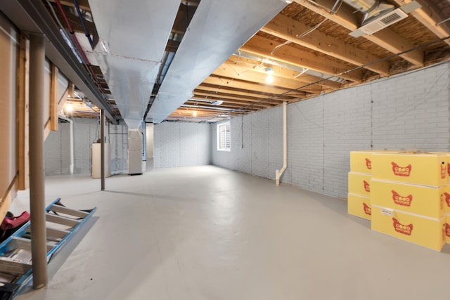 below grade area featuring gas water heater, visible vents, brick wall, and heating unit