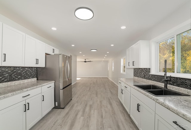 kitchen with light wood-type flooring, tasteful backsplash, ceiling fan, sink, and white cabinetry