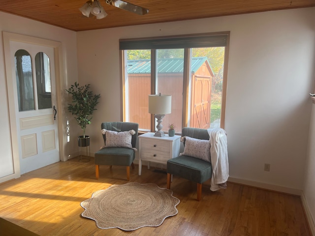 living area with light hardwood / wood-style floors, ceiling fan, and wooden ceiling