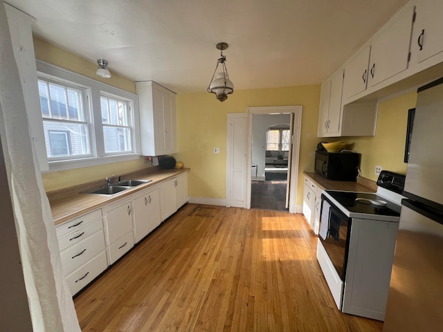 kitchen with white cabinets, electric range, plenty of natural light, and hanging light fixtures