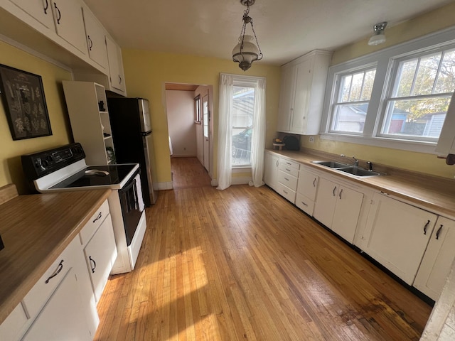 kitchen featuring sink, hanging light fixtures, white range oven, white cabinets, and light wood-type flooring