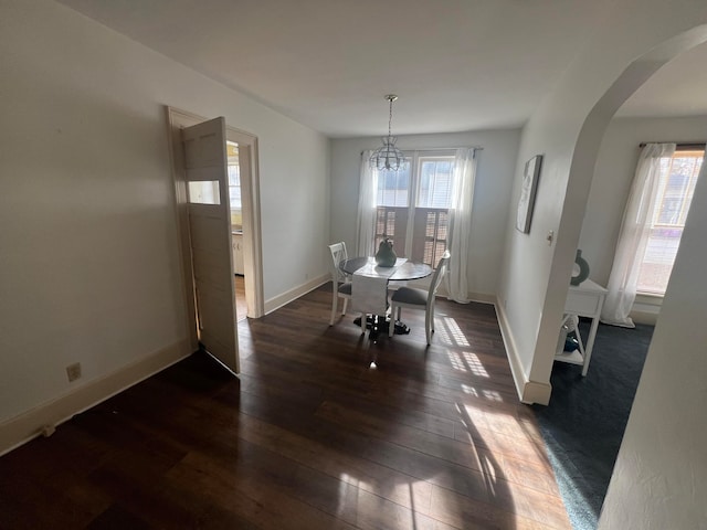 dining space with plenty of natural light, dark wood-type flooring, and a notable chandelier