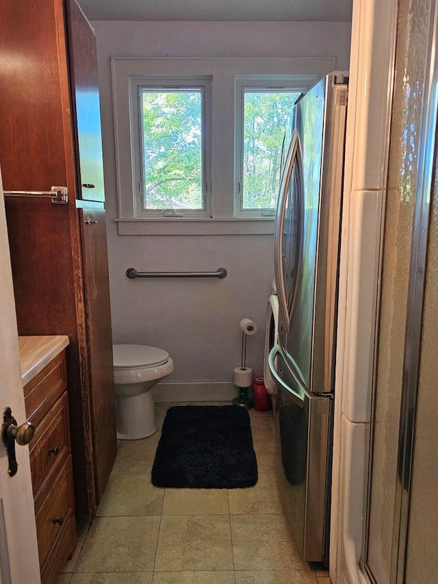 bathroom featuring tile patterned flooring, vanity, toilet, and walk in shower