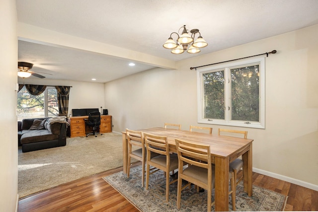 dining room with beamed ceiling, ceiling fan with notable chandelier, and hardwood / wood-style flooring