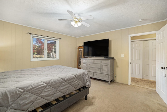 carpeted bedroom with a textured ceiling, a closet, ceiling fan, and ornamental molding