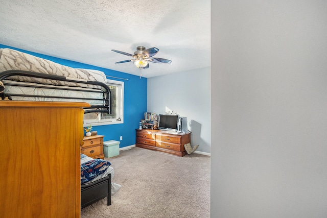 bedroom with ceiling fan, light colored carpet, and a textured ceiling