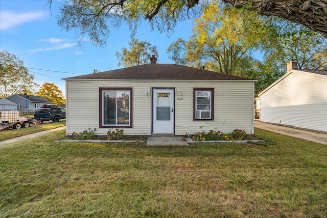 bungalow featuring cooling unit and a front lawn