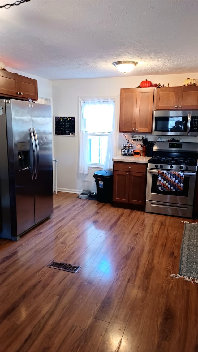 kitchen featuring a textured ceiling, stainless steel appliances, and dark hardwood / wood-style floors