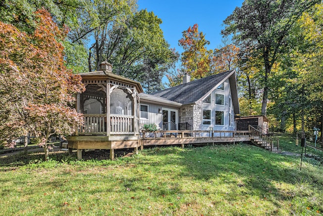 rear view of house with a gazebo, a deck, and a lawn