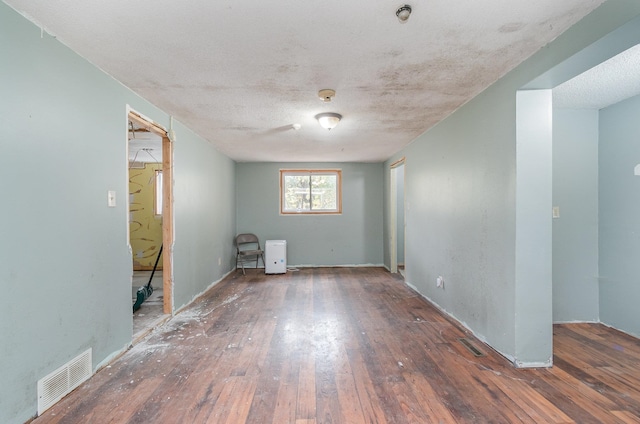 empty room with a textured ceiling and dark wood-type flooring