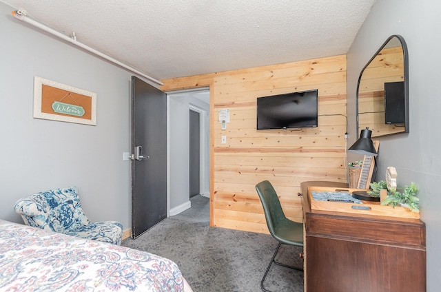 carpeted bedroom featuring a textured ceiling and wooden walls