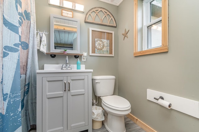 bathroom featuring curtained shower, hardwood / wood-style flooring, vanity, and toilet