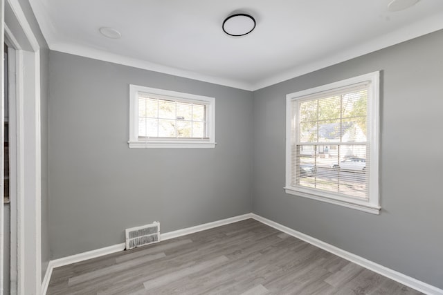 empty room featuring light wood-type flooring and crown molding