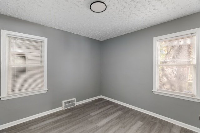 spare room with a textured ceiling and hardwood / wood-style flooring