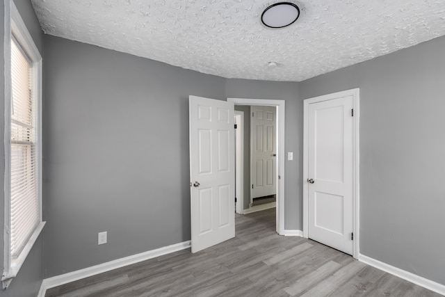 unfurnished bedroom featuring a textured ceiling and light hardwood / wood-style flooring