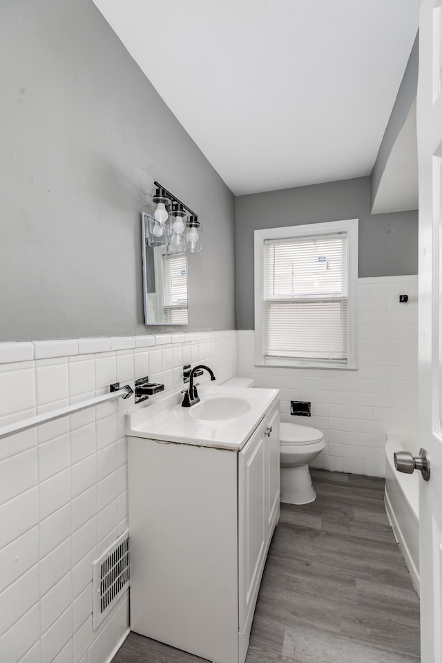 bathroom featuring hardwood / wood-style flooring, vanity, toilet, and tile walls