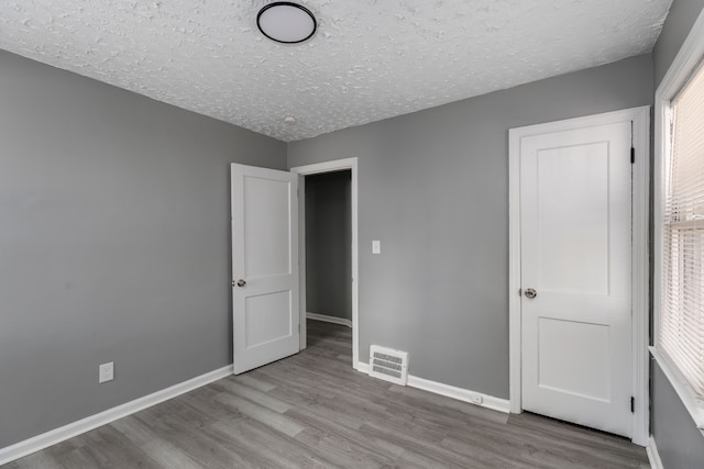 unfurnished bedroom with a textured ceiling and light hardwood / wood-style floors