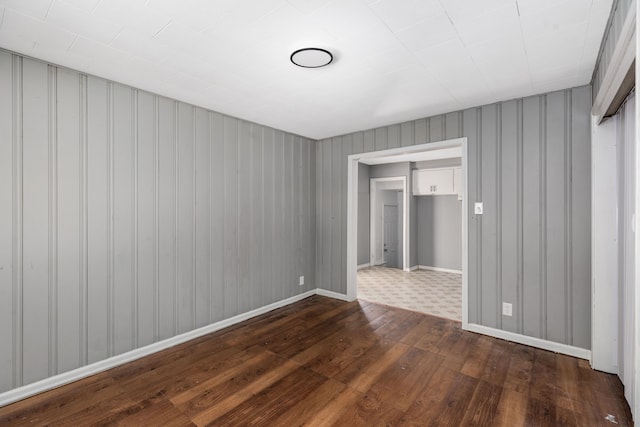 spare room with dark wood-type flooring and wood walls