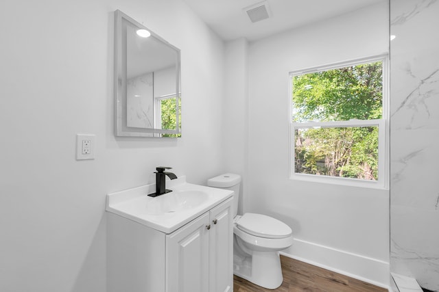 bathroom with vanity, toilet, wood-type flooring, and tiled shower