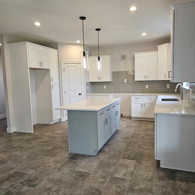 kitchen featuring a kitchen island, decorative backsplash, sink, white cabinetry, and hanging light fixtures