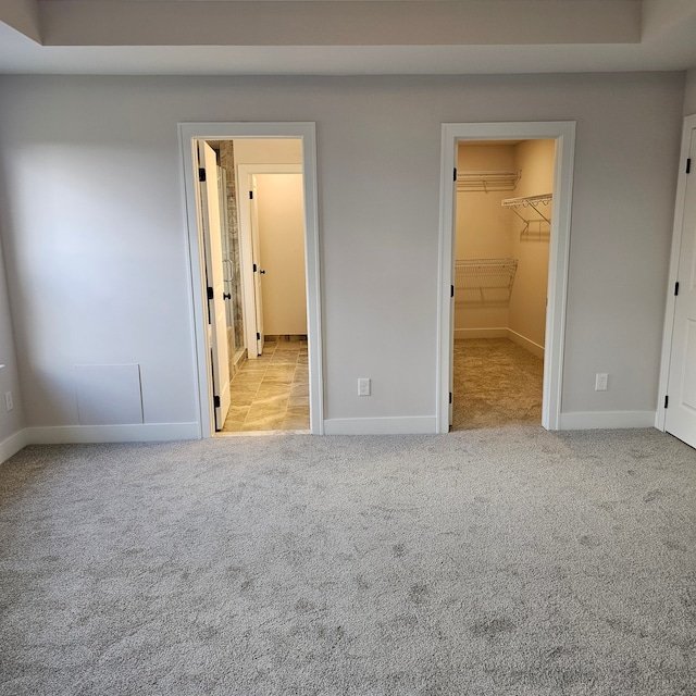 unfurnished bedroom featuring light carpet, a closet, and a walk in closet