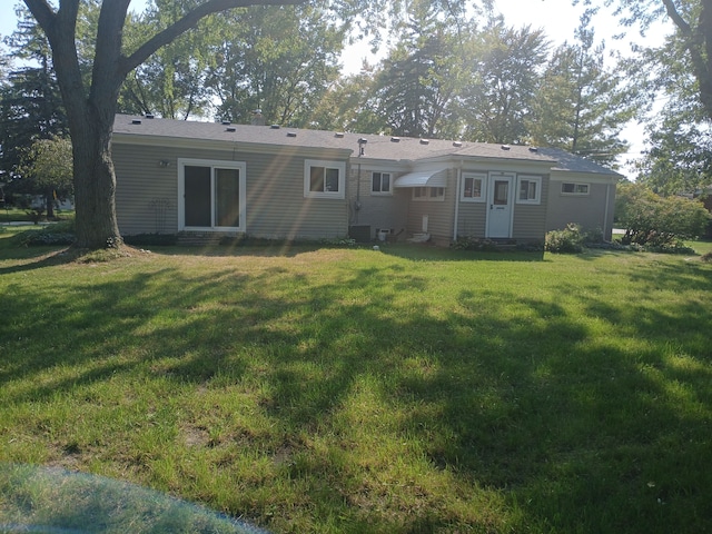 rear view of house featuring central AC unit and a yard