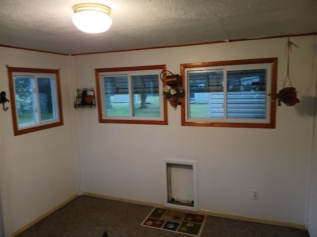 spare room featuring dark carpet and a textured ceiling