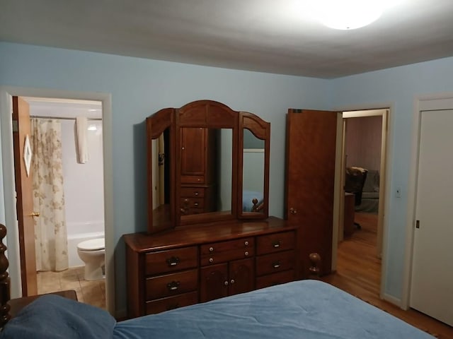 bedroom featuring light wood-type flooring, ensuite bath, and a closet