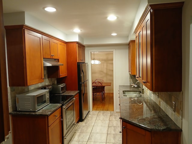 kitchen featuring light tile patterned floors, stainless steel appliances, dark stone counters, and sink