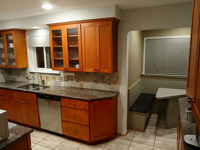 28164 Kendallwood Dr, Farmington Hills, MI 48334 - kitchen with stainless steel dishwasher, a sink, tasteful backsplash, dark stone countertops, and glass insert cabinets