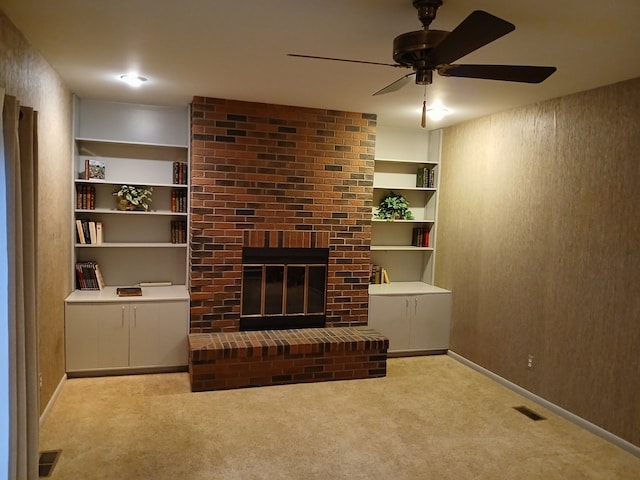 living room with ceiling fan, light colored carpet, built in features, and a brick fireplace