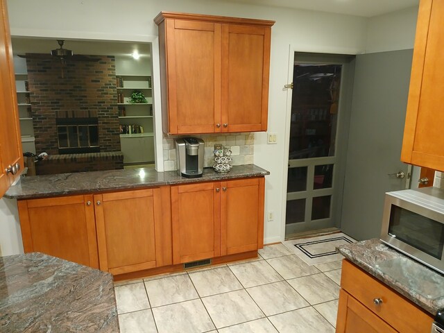 28164 Kendallwood Dr, Farmington Hills, MI 48334 - kitchen featuring stainless steel microwave, tasteful backsplash, dark stone countertops, and brown cabinetry