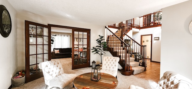 living area featuring a textured ceiling, light hardwood / wood-style flooring, and french doors