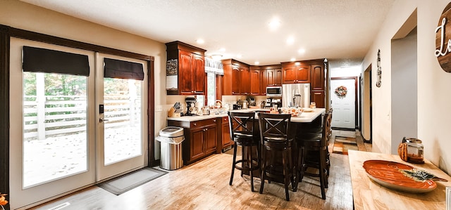 kitchen featuring a breakfast bar, a center island, a textured ceiling, light hardwood / wood-style floors, and stainless steel appliances