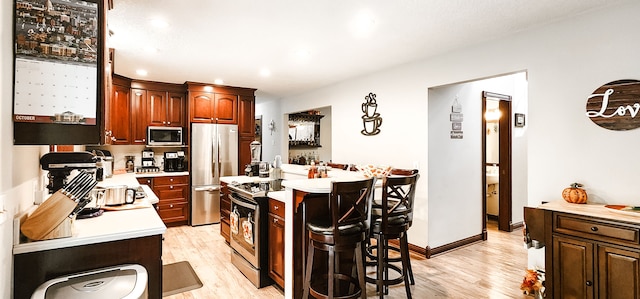 kitchen with a kitchen bar, light wood-type flooring, and appliances with stainless steel finishes