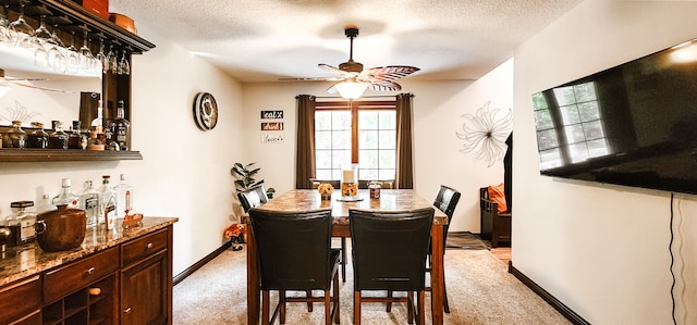 carpeted dining room featuring ceiling fan, indoor bar, and a textured ceiling