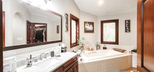 bathroom featuring vanity and tiled bath