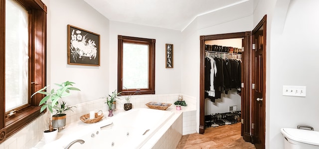 bathroom with hardwood / wood-style floors, toilet, and tiled bath