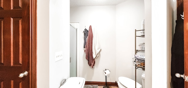 bathroom with toilet, a textured ceiling, and walk in shower