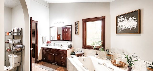 bathroom featuring hardwood / wood-style floors, vanity, and a relaxing tiled tub