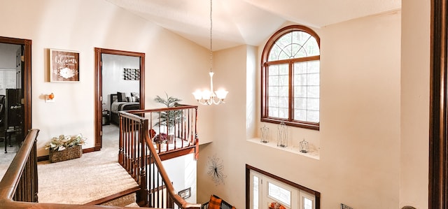 stairway featuring carpet, lofted ceiling, and a chandelier