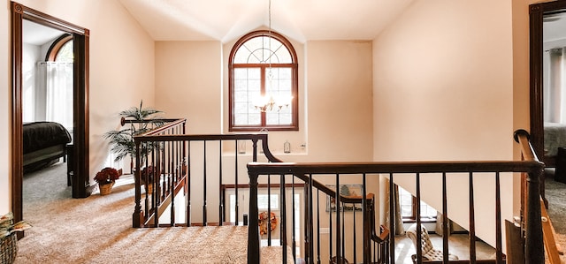 hallway with light colored carpet and lofted ceiling