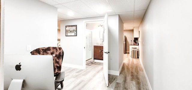 hallway with a paneled ceiling and light hardwood / wood-style flooring