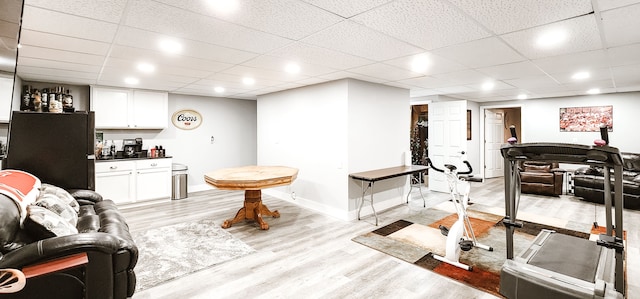 living room featuring a drop ceiling, bar, and light hardwood / wood-style flooring