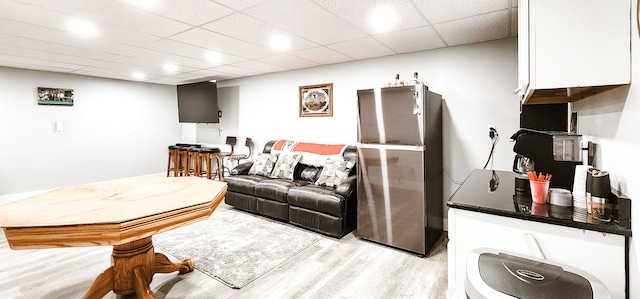 living room with light hardwood / wood-style flooring and a drop ceiling