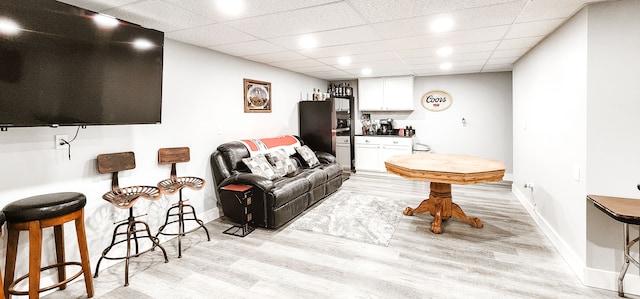 living room with a paneled ceiling and light hardwood / wood-style flooring