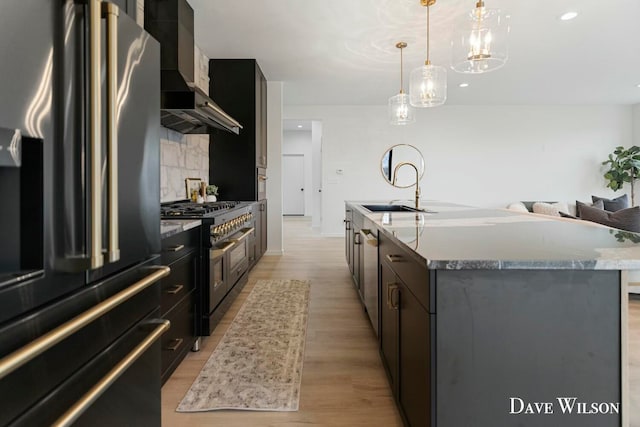 kitchen featuring a center island with sink, sink, hanging light fixtures, light hardwood / wood-style flooring, and stainless steel appliances