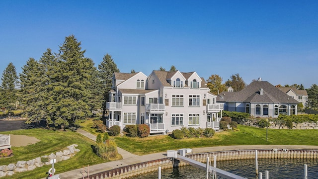 back of property featuring a water view and a lawn