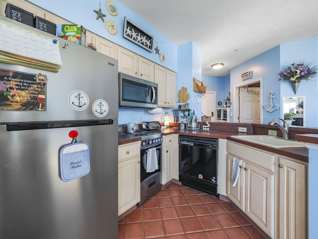 kitchen featuring black appliances, dark tile patterned floors, sink, and cream cabinetry